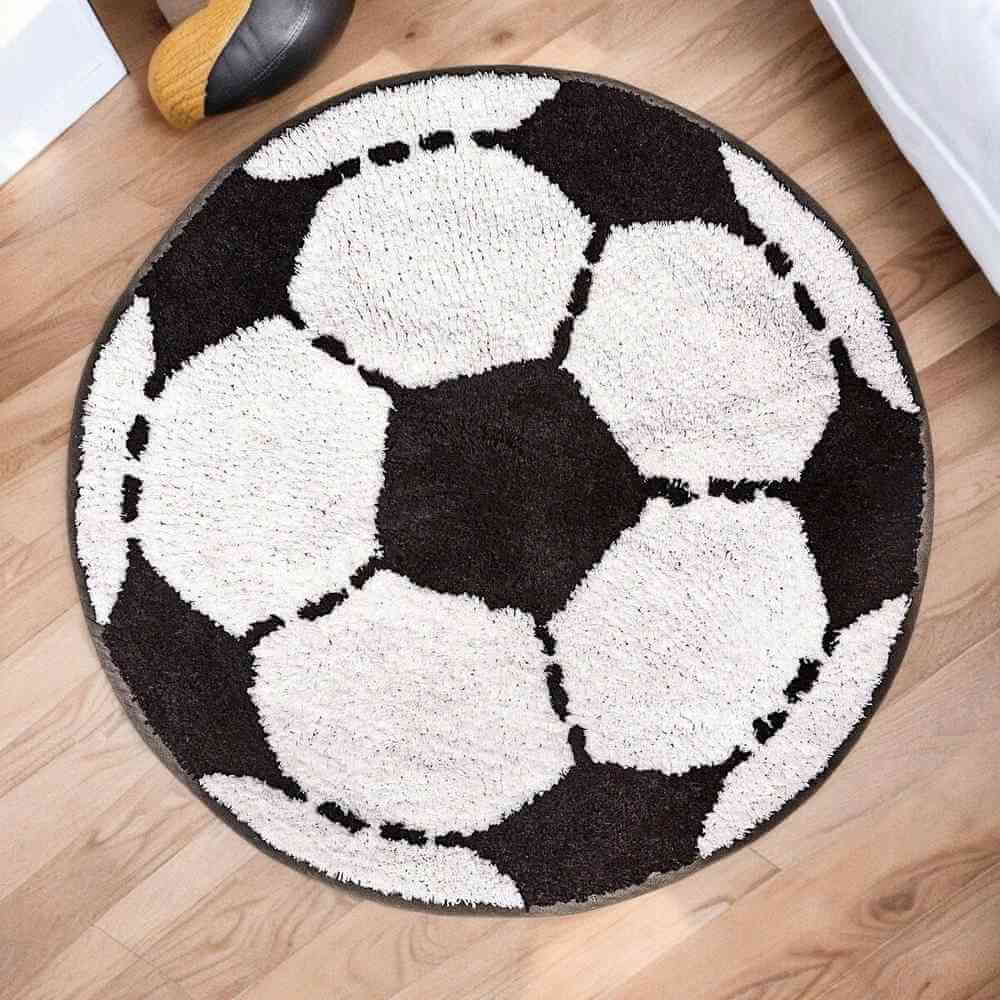 Round football-shaped rug with black-and-white soccer ball design and curved edge border.