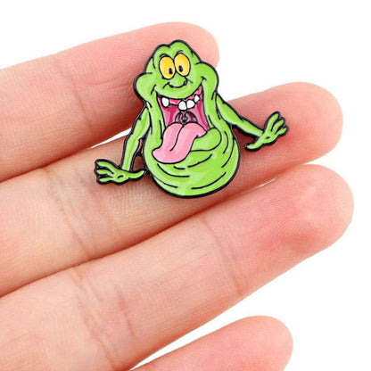 Slimer enamel pin on hand, green ghost character with pink tongue and big teeth grin