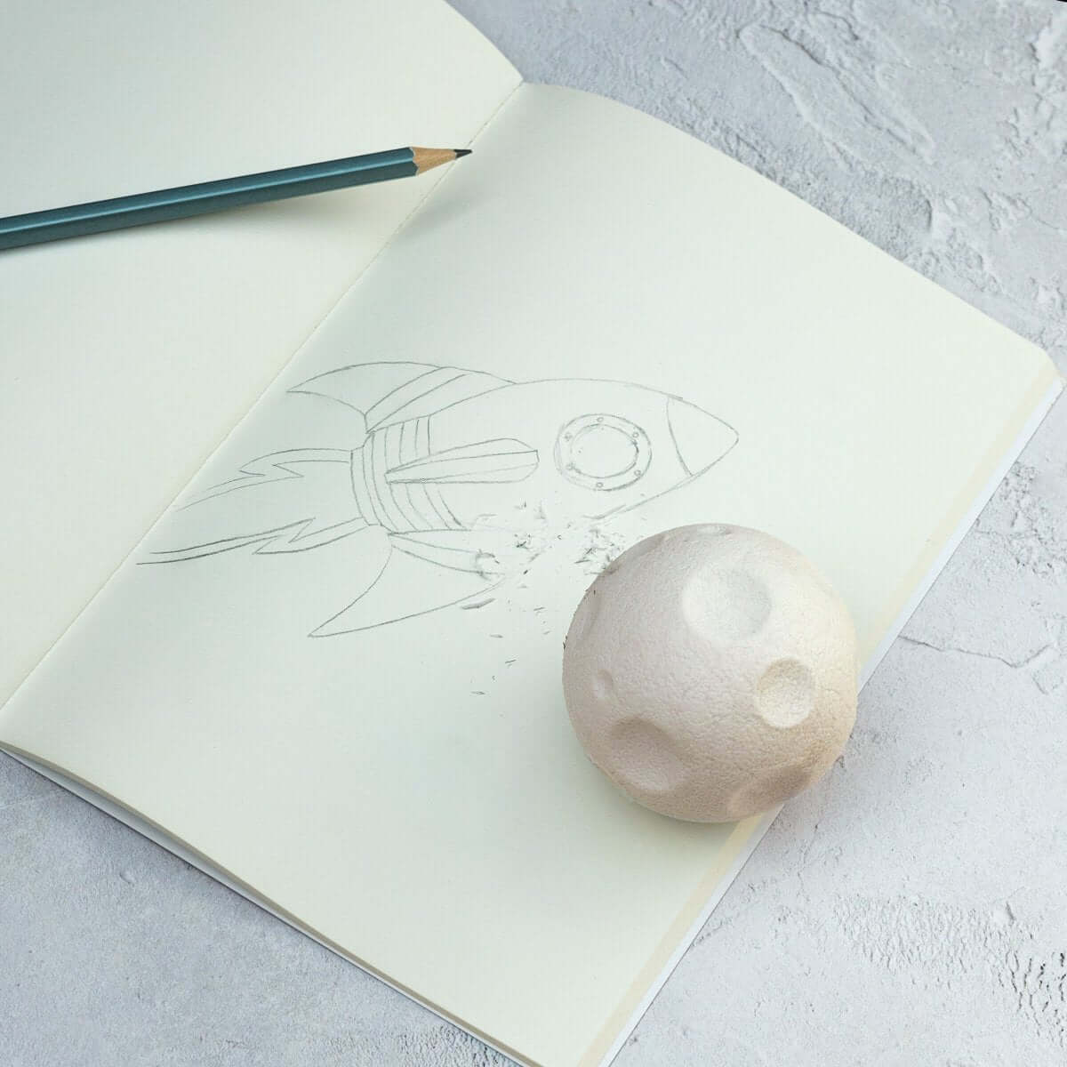 Moon-shaped rubber eraser on a sketchbook page with line art