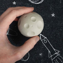 Hand holding cream moon-shaped rubber eraser with crater-like embossed details