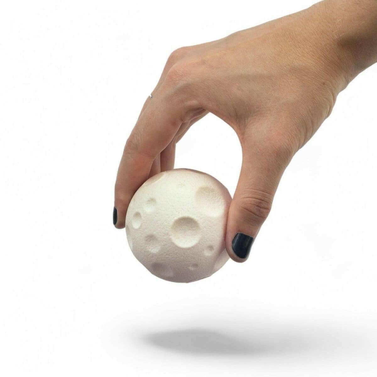 Moon-shaped rubber eraser with light cream surface and embossed crater patterns
