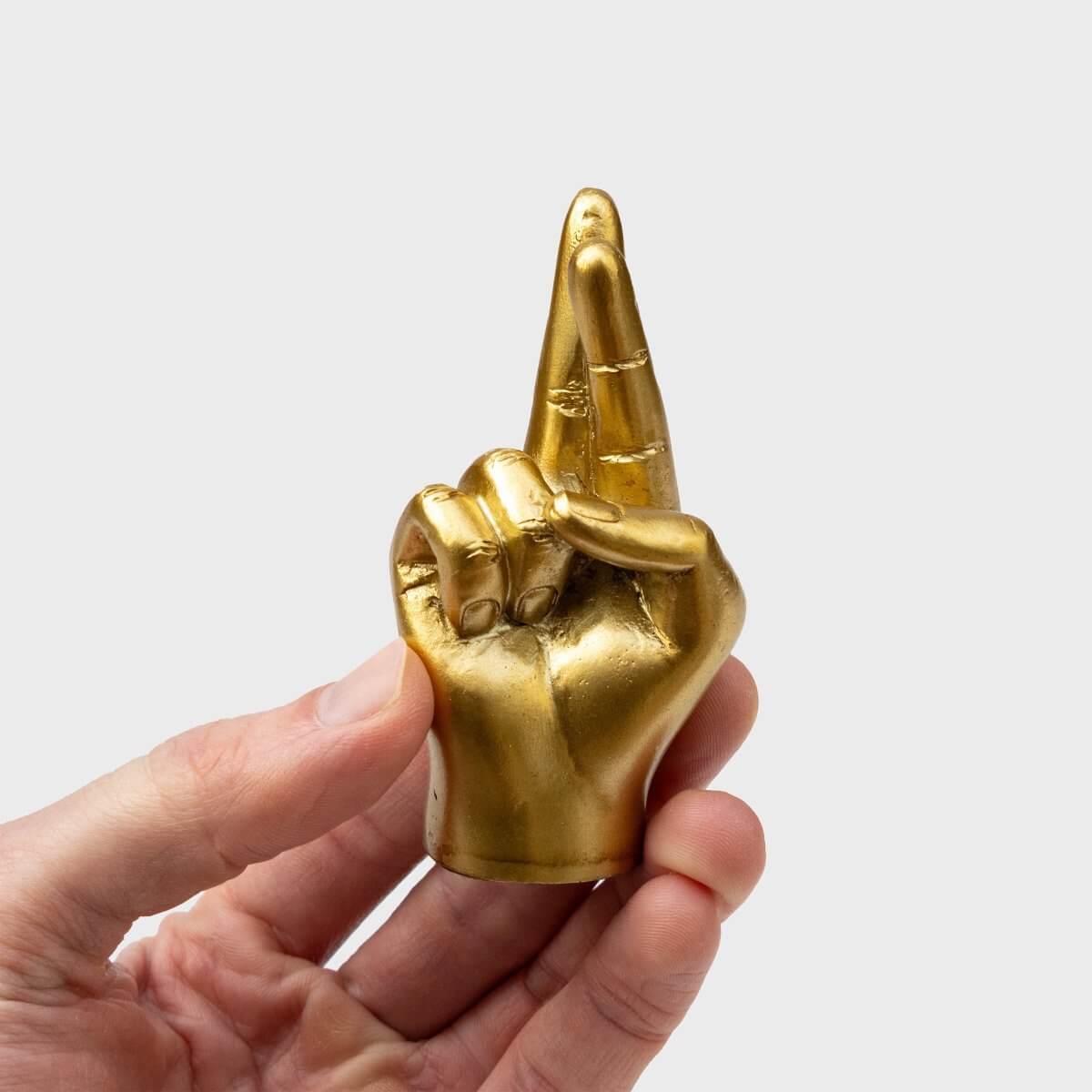 Gold tone crossed-fingers lucky charm ring holder, close-up