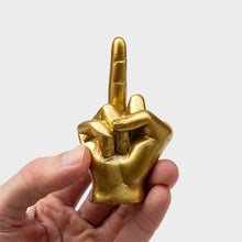 Golden middle-finger hand gesture charm held in hand
