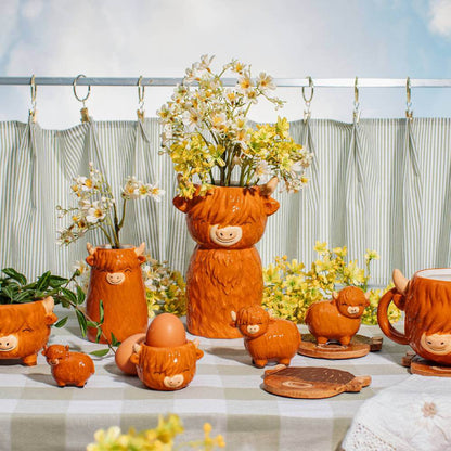 Set of orange Highland cow ceramic tableware pieces, including an egg cup with face