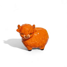Glossy orange Highland cow figurine, closed eyes and smiling mouth, small standing