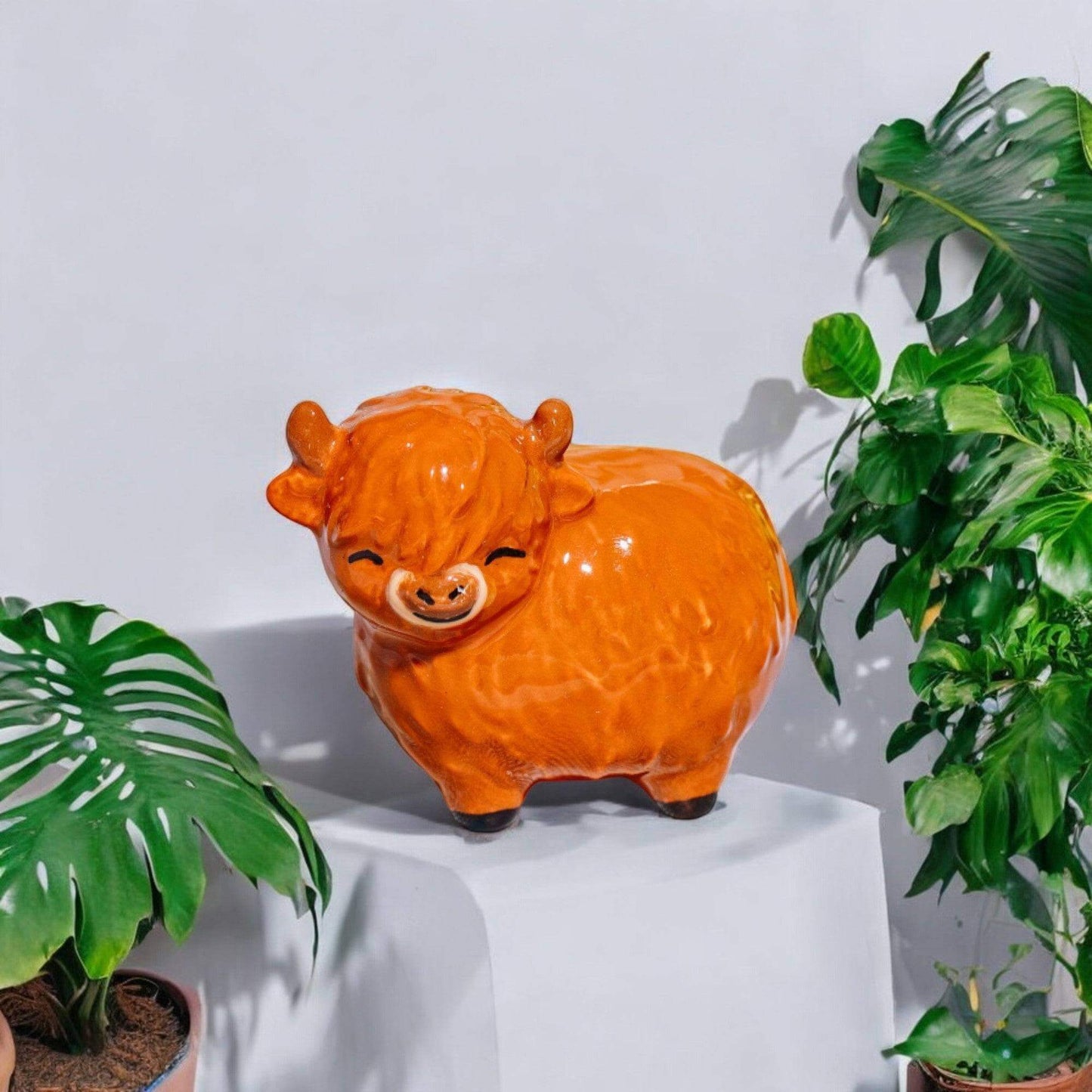 Glossy orange Highland cow figurine with face and snout, small standing sculpture