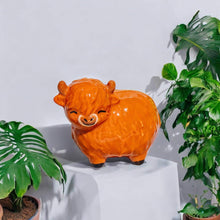 Glossy orange Highland cow figurine with face and snout, small standing sculpture