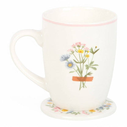White ceramic mug with bouquet in orange pot; pink rim and flower-pattern coaster base