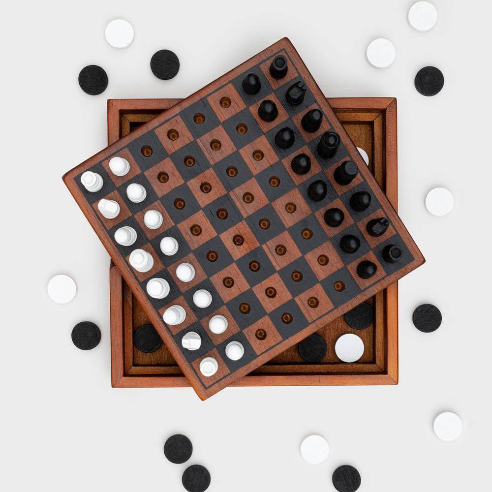 Wooden chess and checkers boards with dark and white round pieces scattered around
