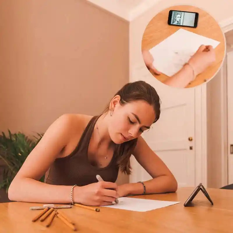Black phone holder stand on a desk holding a phone while writing