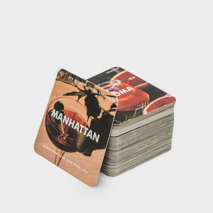 Stacked cocktail recipe coasters featuring the Manhattan cocktail card design.