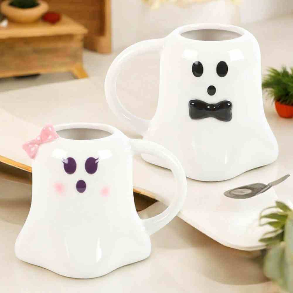 Ghost-shaped ceramic mug with pink bow, purple eyes and frown, white body