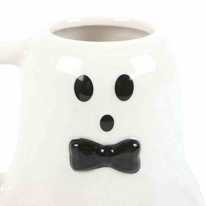 Ghost-shaped mug close-up: black eyes, black bow mouth, white ceramic