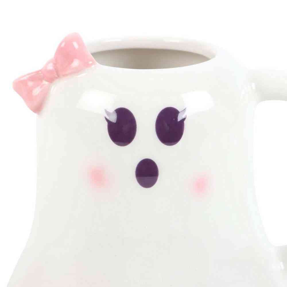 Ghost-shaped mug close-up: pink bow, purple eyes and nose on white ceramic
