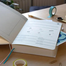 Baby years journal opened to printed pages with circular icons and checklist lines