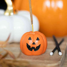 Pumpkin-shaped incense stick holder with jack-o'-lantern face, orange