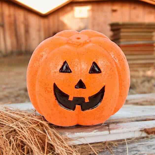 Orange pumpkin incense stick holder with carved jack-o'-lantern face