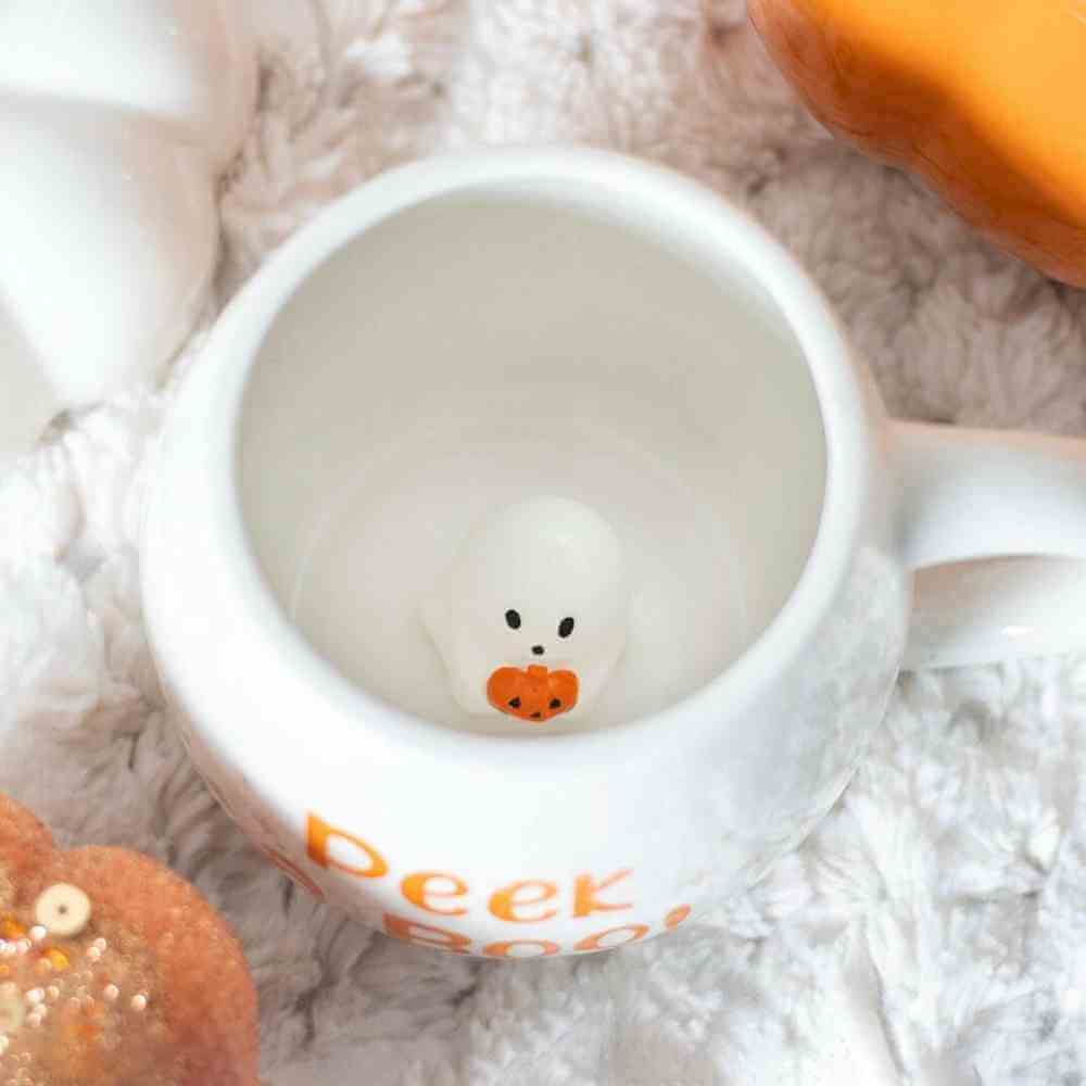 White mug interior with small ghost face and orange pumpkin; rounded rim