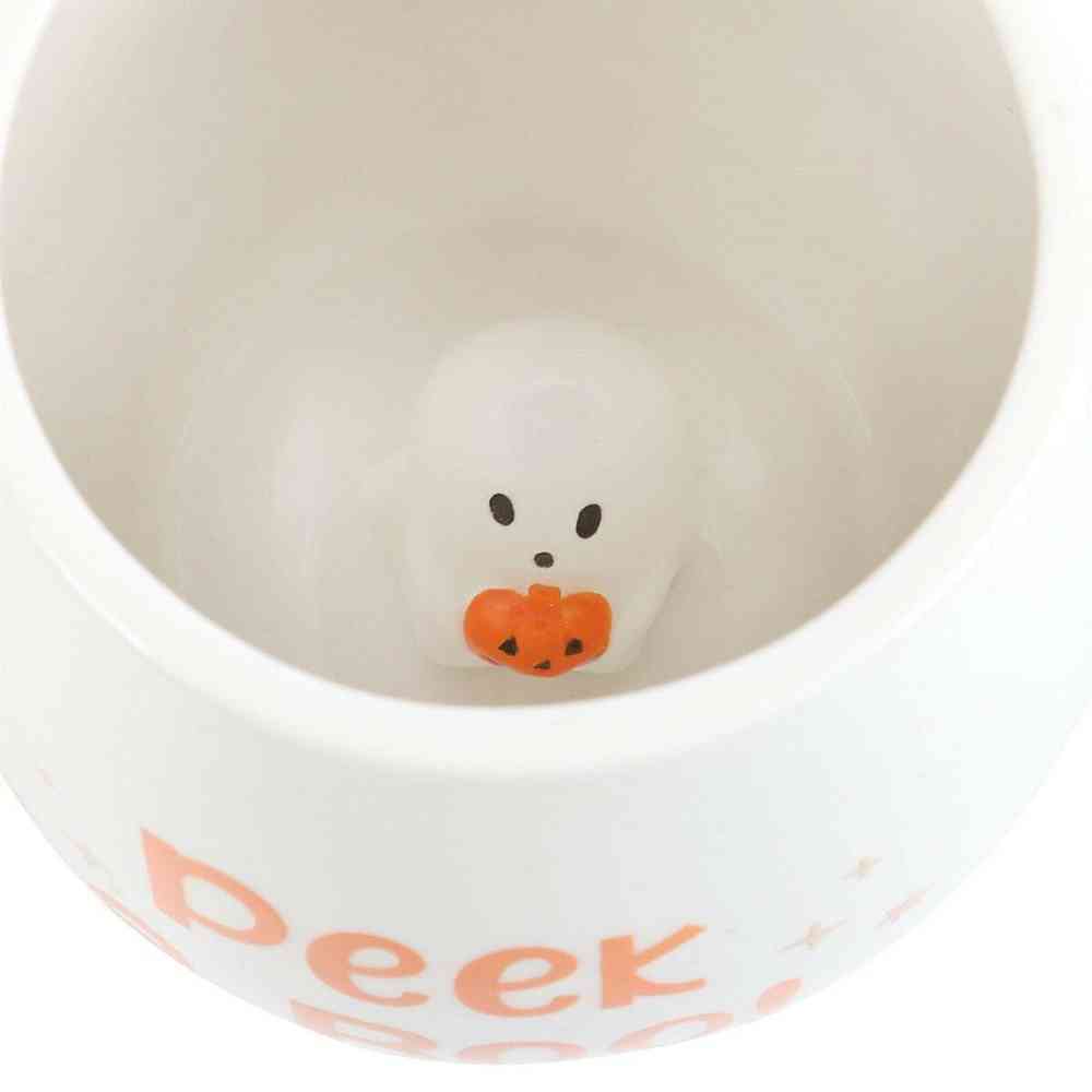 White mug interior close-up with ghost face and orange pumpkin at base