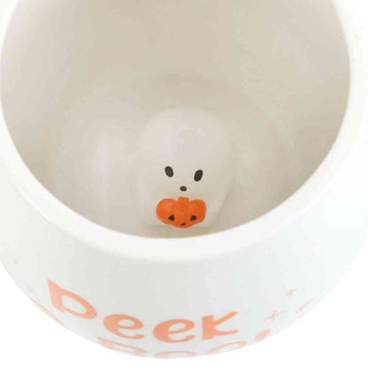 White mug interior close-up with ghost face and orange pumpkin at base