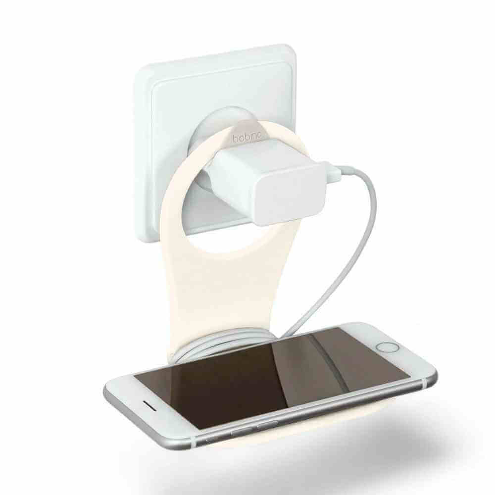 Phone holder with cable tidy, cream wall mount with white cable, holding a smartphone