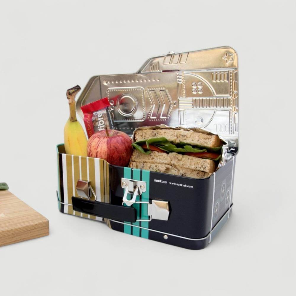 Open rocket lunch box with sandwich, fruit, and vegetables inside the compartment.