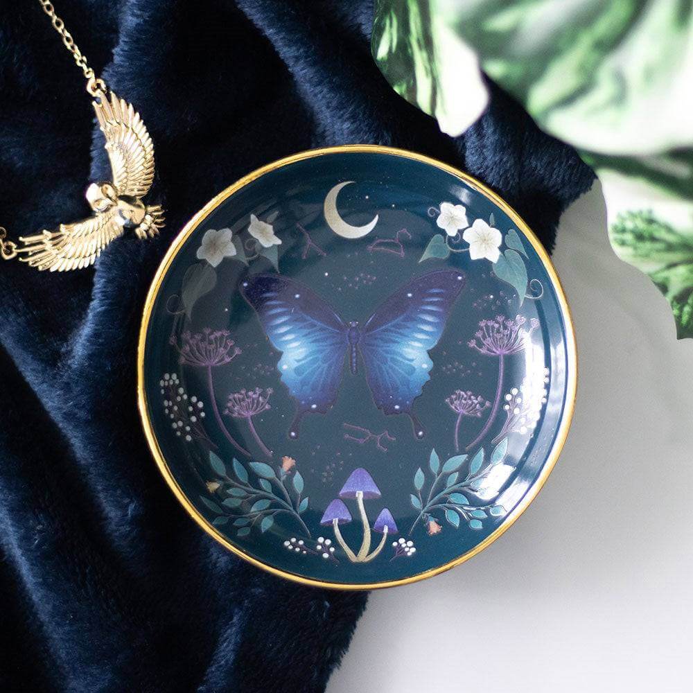 Round trinket dish with blue moth, moon, floral accents, and gold rim