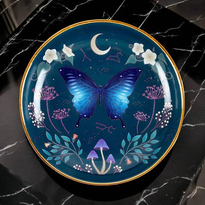 Round trinket dish with blue moth and moon motif on dark blue, gold rim
