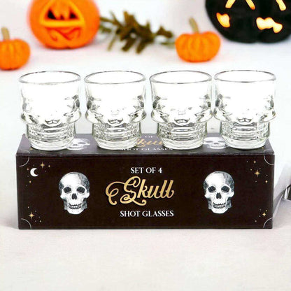 Set of 4 clear skull shot glasses on gift box, glass faces show etched skulls