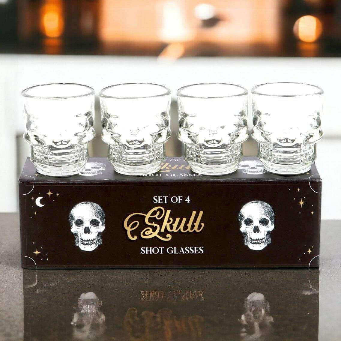 Set of 4 clear skull shot glasses on gift box, skull faces on front of glasses