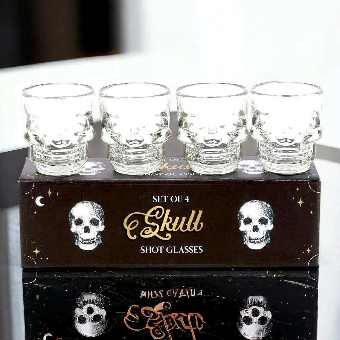 Set of 4 clear skull shot glasses on gift box, skull faces visible on each glass