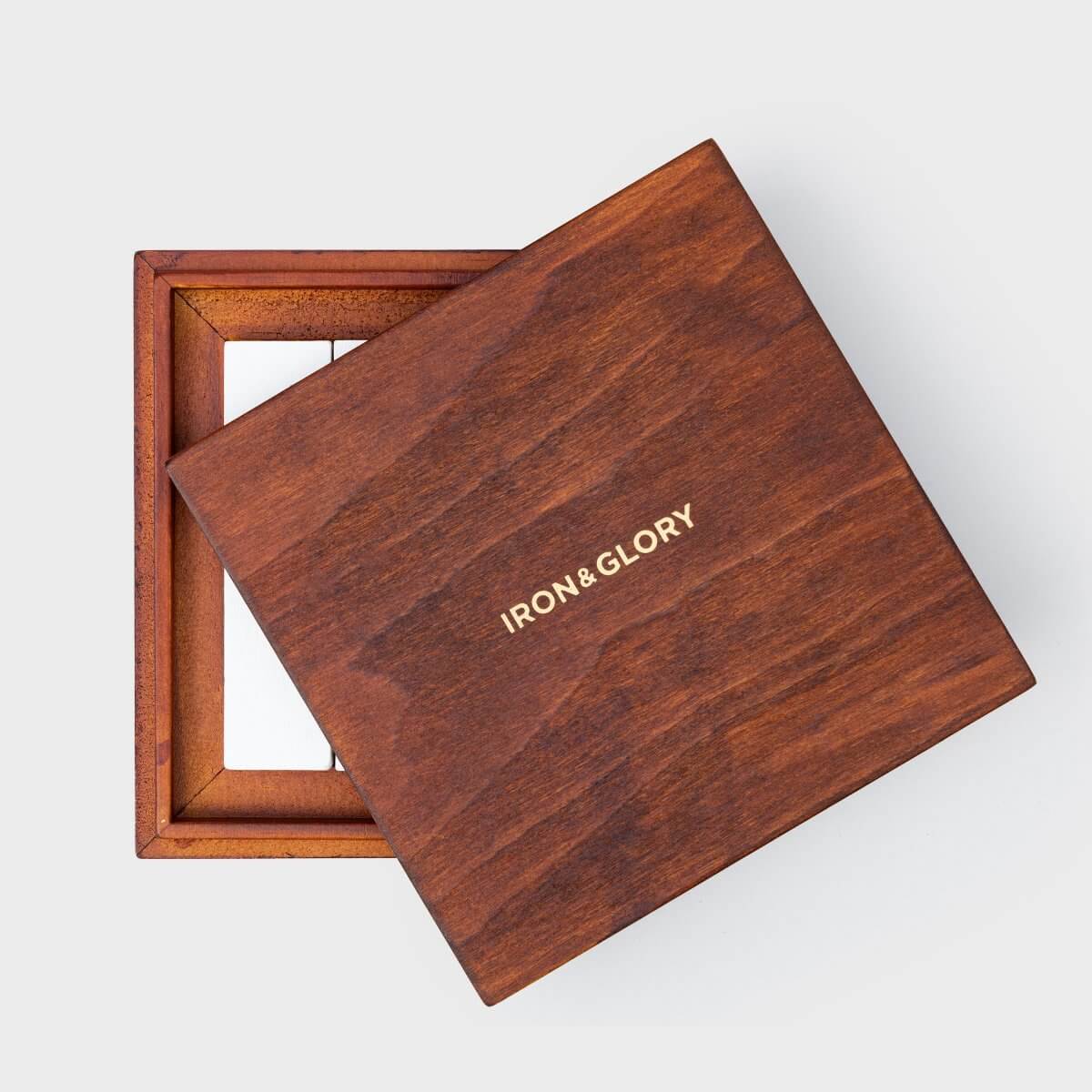 Wooden puzzle box cover with IRON&GLORY logo, partly over framed board