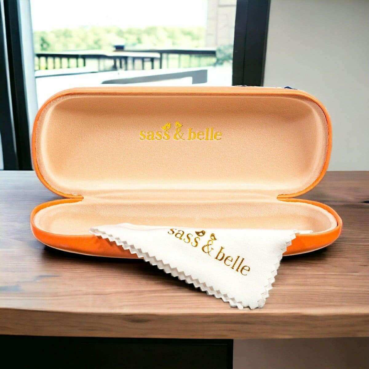 Orange glasses case open with white cleaning cloth and cushioned interior.