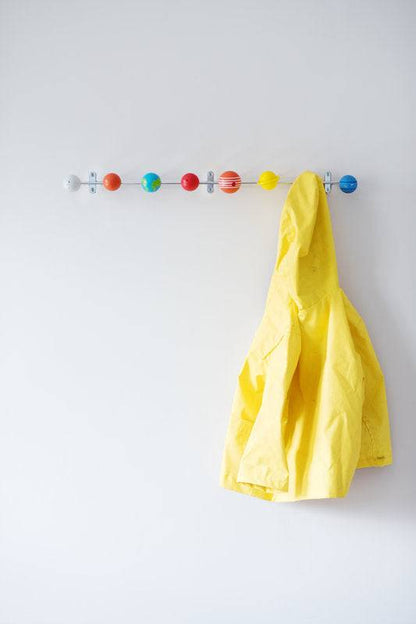 Solar system coat rack with colorful wood planet hooks and a yellow cloth hanging