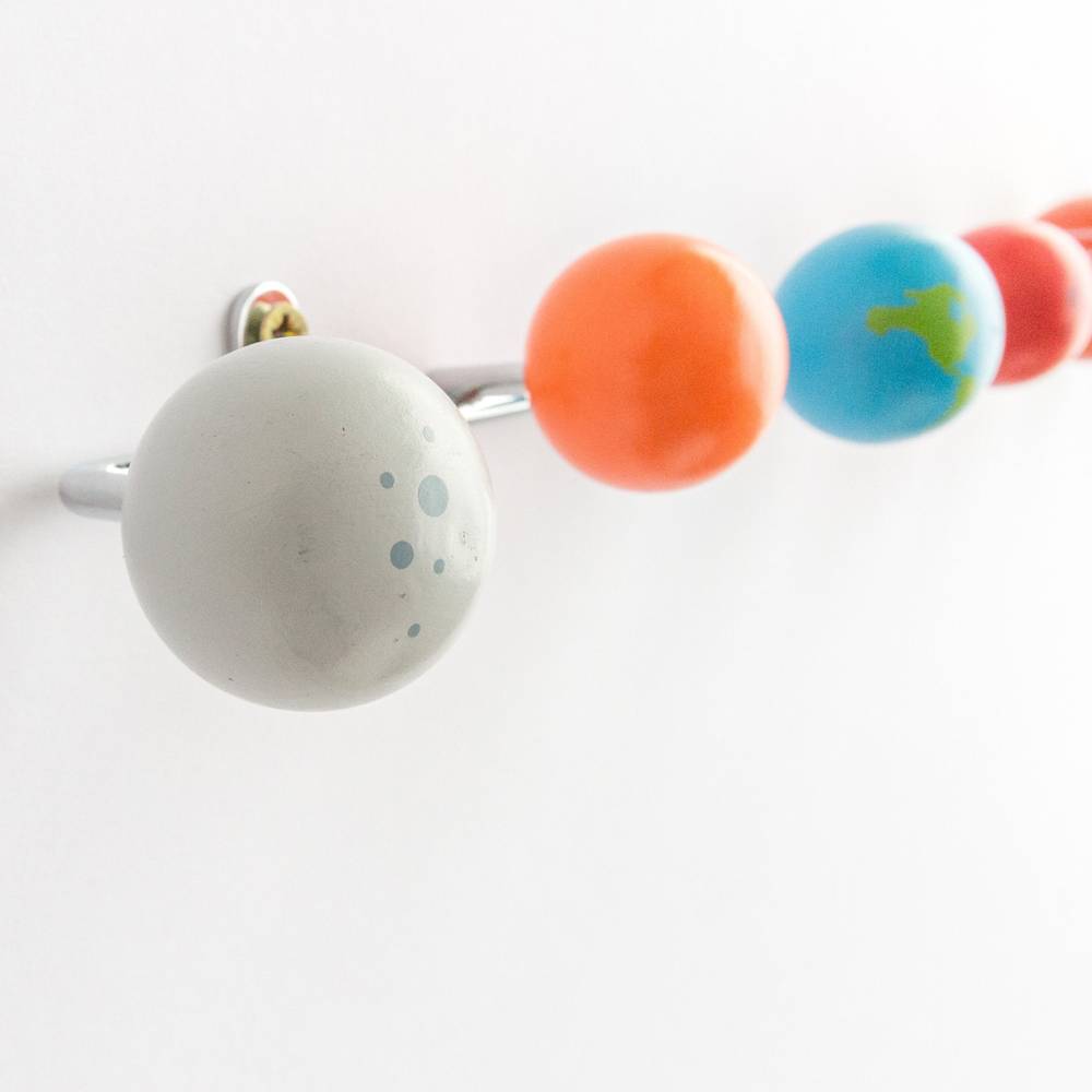 Coat rack hook with painted wooden planet pieces, including a gray moon and orange planet