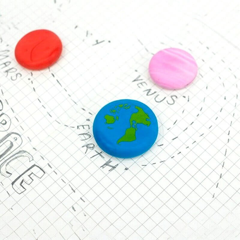 Blue Earth planet eraser on grid paper with red and pink round erasers nearby