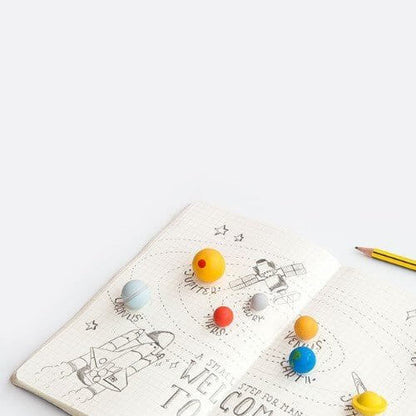 Planet-themed erasers on graph sheet: small blue, orange, yellow, red and gray