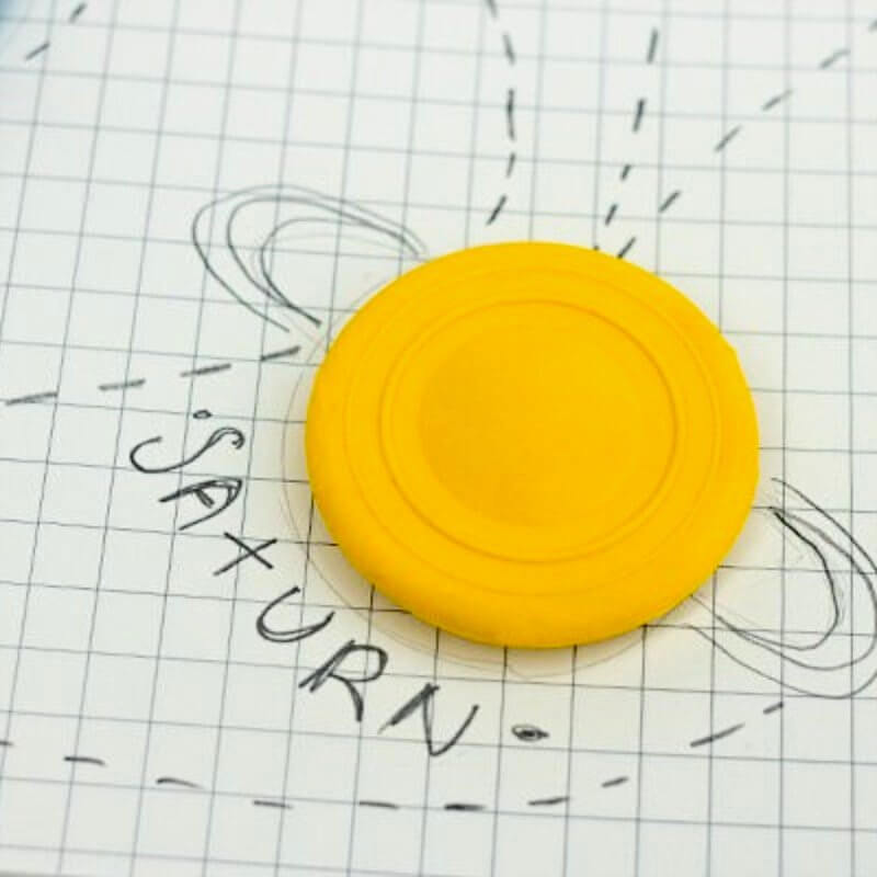 Round yellow planet eraser on grid paper with dashed lines and scribble marks