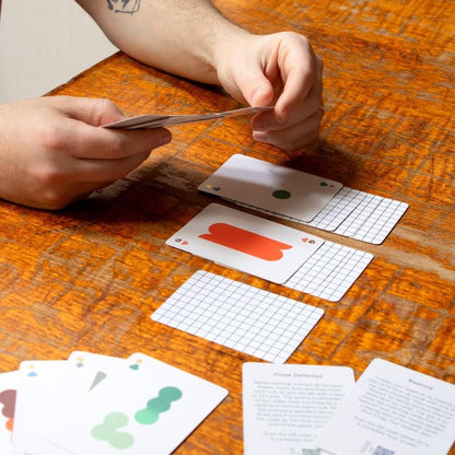 Hands dealing Solo Mello solitaire cards on a wooden tabletop