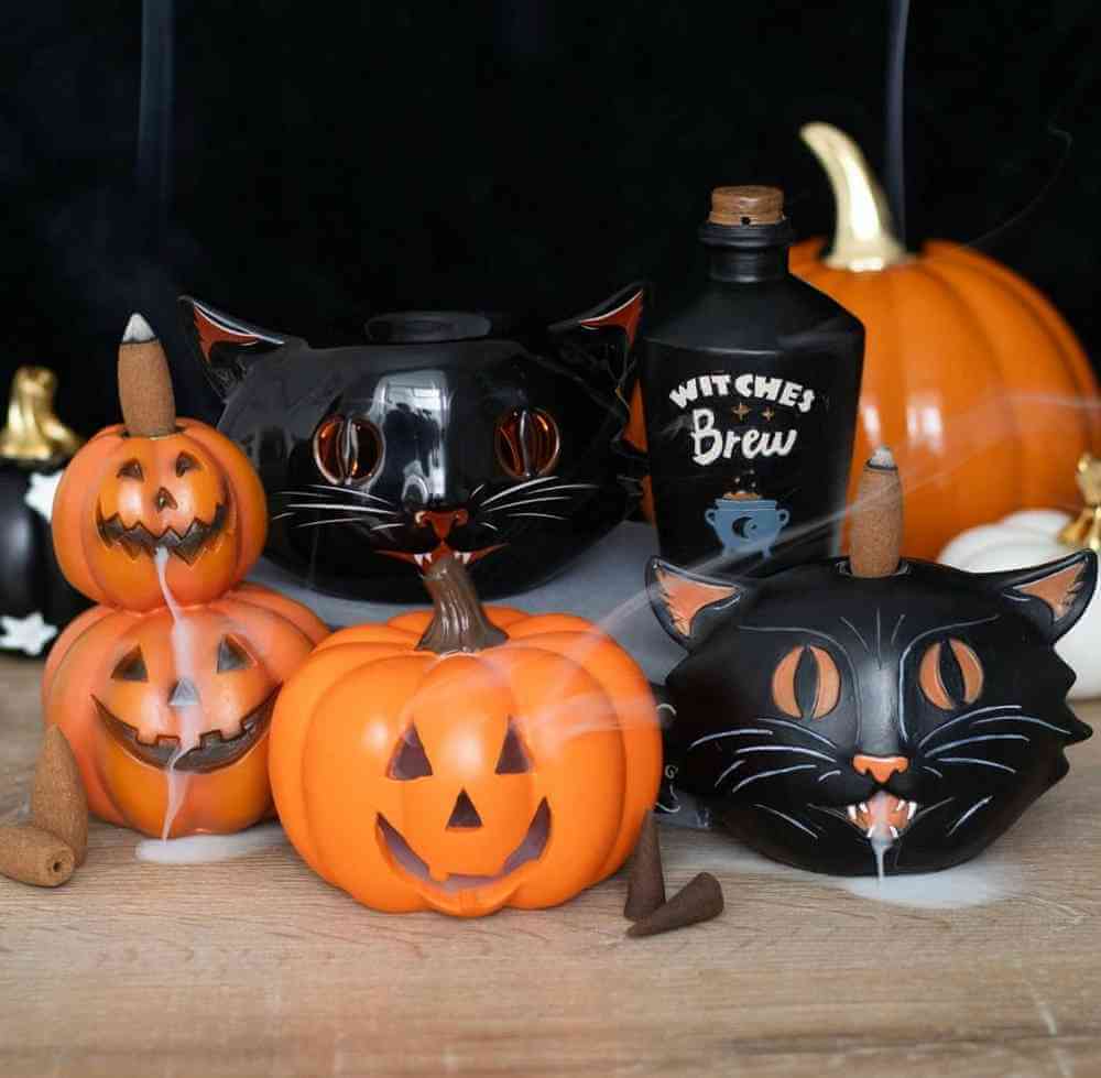 Stacked pumpkin jack-o-lantern backflow incense burner with incense stick, among Halloween decor