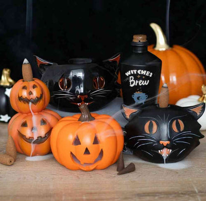 Stacked pumpkin jack-o-lantern backflow incense burner with incense stick, among Halloween decor
