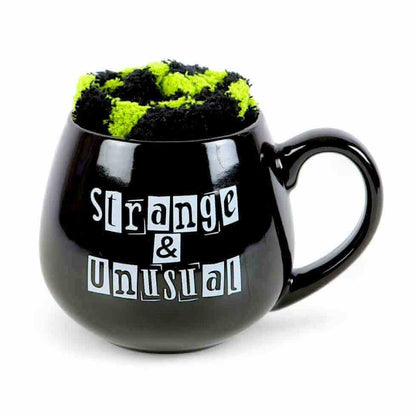 Black novelty mug with green fuzzy top and 'Strange & Unusual' slogan