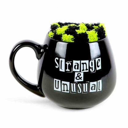 Front-facing black novelty mug with green fuzzy top and 'Strange & Unusual' print