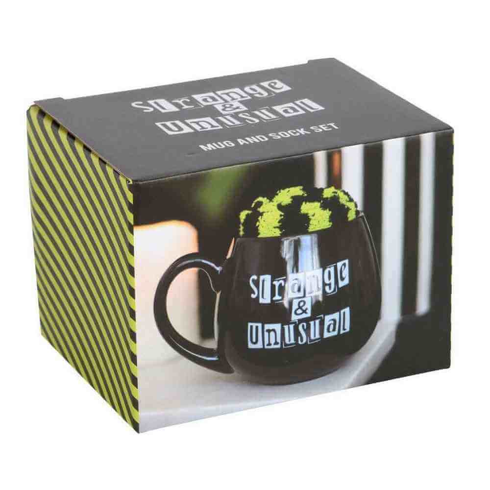 Gift set box with black mug graphic, 'Strange & Unusual' logo, and green fuzzy top