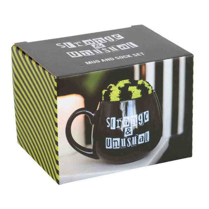 Gift set box with black mug graphic, 'Strange & Unusual' logo, and green fuzzy top