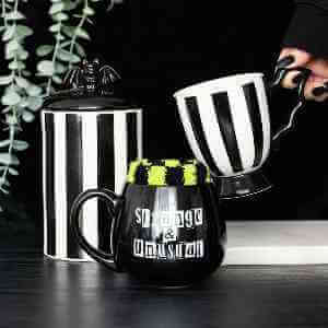 Black mug labeled 'Strange & Unusual' with green fuzzy top