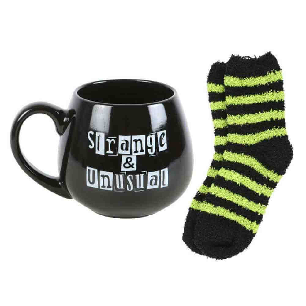Black mug with 'Strange & Unusual' print and black socks with neon green stripes