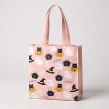 Pink Halloween tote bag with ghost, pumpkin, and cat faces print; front view handles