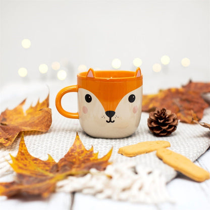 Fox face ceramic mug in orange and cream with curved handle and ears on rim.