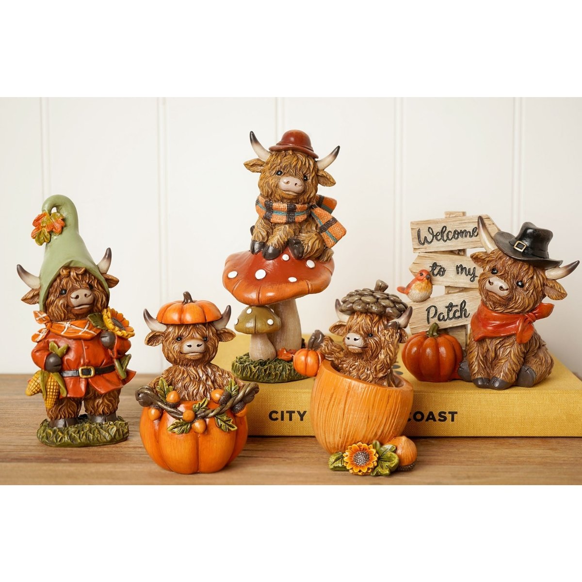 Decorative country-style animal and cow figurines with pumpkins displayed on a shelf